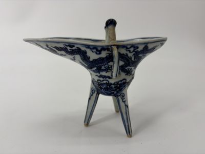 un petit vase bleu et blanc d'où sort un bâton en bois