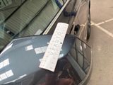 a car with a ticket attached to it ' s windshield