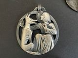 a silver pendant with a picture of a man and a dog on it