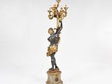 an antique bronze figurine of a man holding a candelabra