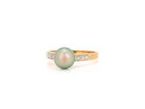 une bague avec une perle verte et des diamants sur fond blanc