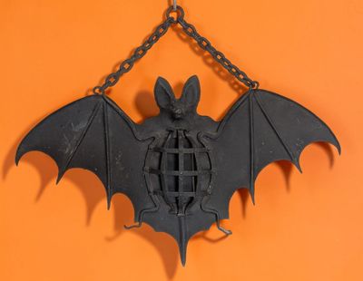 une chauve-souris suspendue à une chaîne sur un mur orange