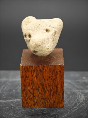 un gros plan sur une sculpture représentant une tête d'ours posée sur un bloc de bois