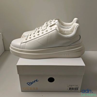 les baskets blanches sont posées sur une boîte blanche