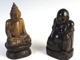 two statues of buddhas sitting on top of a wooden table