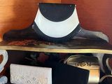 a black and white hat sitting on top of a wooden shelf