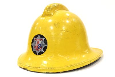 un casque de pompier jaune orné d'un insigne