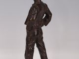 bronze statue of a boy standing on a block with his hands on his hips