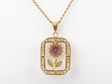 a close up of a gold necklace with a flower on it