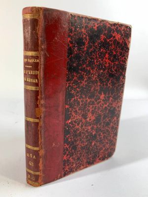 un vieux livre à la couverture rouge posé sur une table blanche