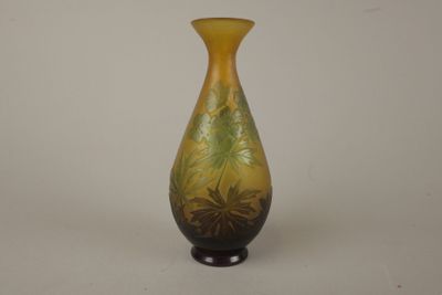 un vase jaune et vert posé sur une surface blanche