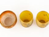 three small yellow cups sitting next to each other on a white surface