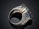 a close up of a ring with blue sapphires and diamonds on a black surface