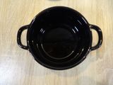 a black pot sitting on a wooden table with a spoon