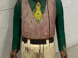 a wooden statue of a man wearing a hat and a green shirt