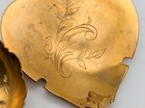 two gold spoons with designs on them sitting next to each other