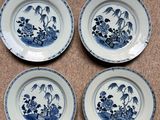 four blue and white plates with birds and flowers on them