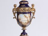a blue and gold vase sitting on a white pedestal