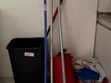 brooms, mop, buckets, and a trash can in a kitchen