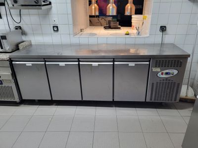 une cuisine équipée de plans de travail en inox et d'un réfrigérateur