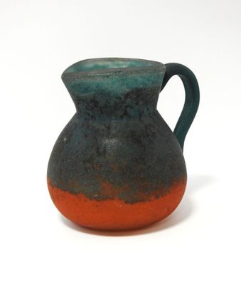 un vase bleu et orange posé sur une surface blanche