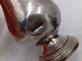 a silver vase on a white table next to a red apple