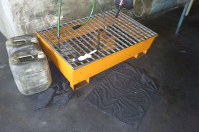 une grille métallique posée au sol, à côté d'un bidon d'essence