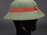 a green helmet with a red band on top of a mannequin head