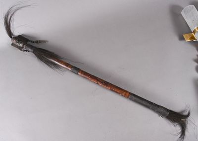 une plume sur un bâton, à côté d'un couteau posé sur une table