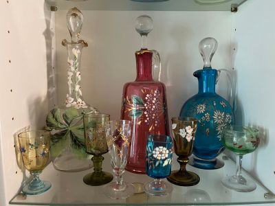 many different colored glass vases and glasses on a shelf