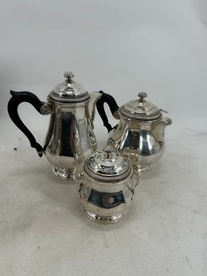 three pieces of silver tea and coffee set on a white surface