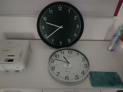 a clock on the wall next to a printer on the desk