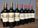 several bottles of wine are lined up on a wooden table