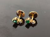 paire de boucles d'oreilles dorées et vertes, ornées de diamants, sur un fond noir