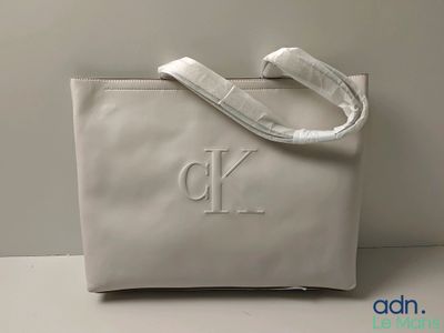 le sac blanc porte un monogramme et est posé sur une table