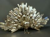 une sculpture en argent représentant un paon, réalisée à partir de cuillères