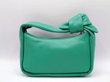 Le petit sac à main vert est orné d'un nœud sur le devant.