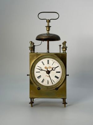 a small clock with a bell on top of it