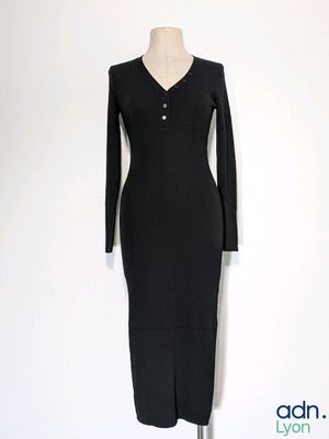 La robe est noire et comporte des boutons au niveau du cou.