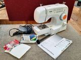 une machine à coudre blanche posée sur une table, à côté d'autres objets