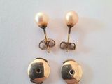 une paire de boucles d'oreilles en perles et en or posées sur une surface blanche