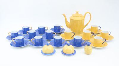 yellow and blue tea set with cups and saucers on a white surface
