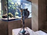 a statue of a fish on a pedestal in front of a fish tank