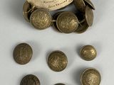 some old brass buttons and a tag on a white surface