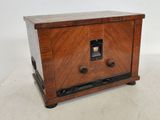 une vieille radio en bois posée sur un meuble blanc