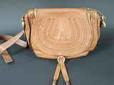 the small brown purse is sitting on the table with a strap around it