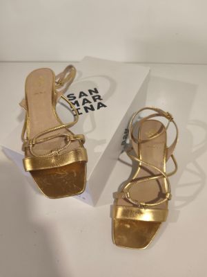 the gold sandals are next to a white box on the table