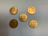 quatre types différents de pièces d'or sur une surface blanche