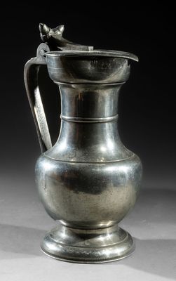 a silver vase with a bird on it on a table