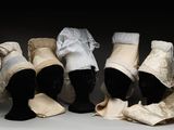 quatre mannequins coiffés de chapeaux et portant des écharpes, exposés dans une pièce sombre